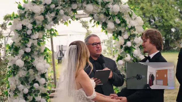 The officiant presides over the wedding ceremony under a floral arch, after final color grading.