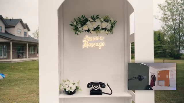 A close-up shot of the "Leave a Message" neon sign inside the white telephone booth prop.