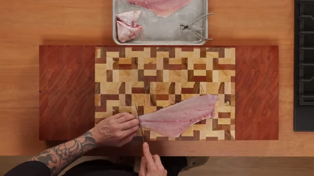 An overhead shot shows a chef making the initial cut to begin skinning a fish fillet