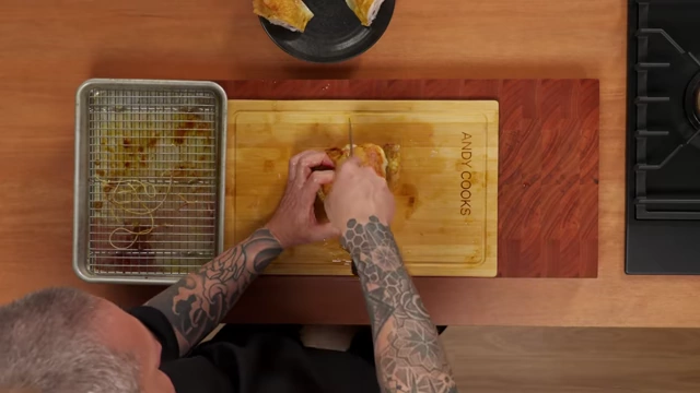 A chef carves a roasted chicken breast by cutting along the sternum bone and following the rib cage