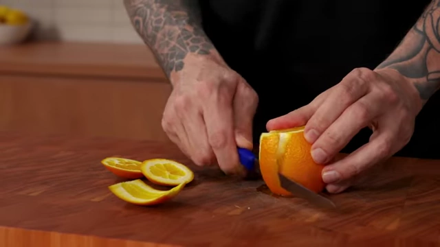 A serrated paring knife effectively peeling and slicing an orange