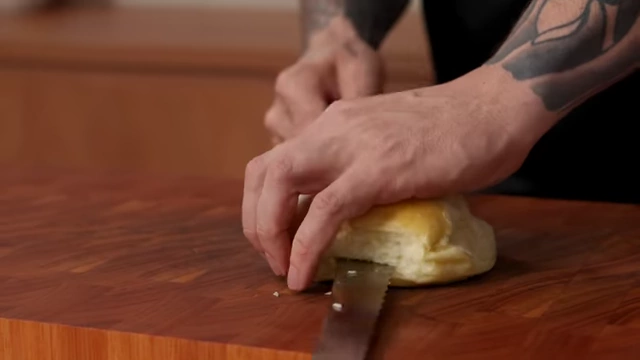 A serr serrated bread knife easily slicing through a roll