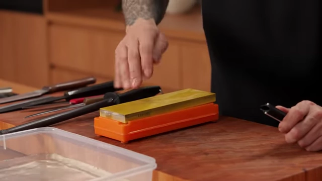 A chef adds water to a wet stone to maintain lubrication during sharpening