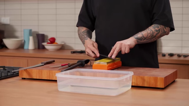 A metal angle guide attached to a knife blade for consistent sharpening on a wet stone