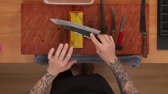 An overhead view of the chef flipping the knife to sharpen the other side of the blade on the wet stone