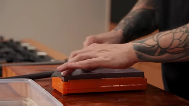 A chef sharpens a knife on a 5000-grit wet stone for a polished finish