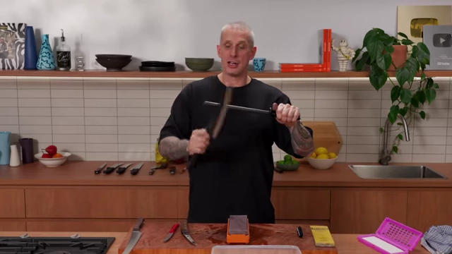 A chef demonstrating the correct technique for honing a knife on a ceramic rod