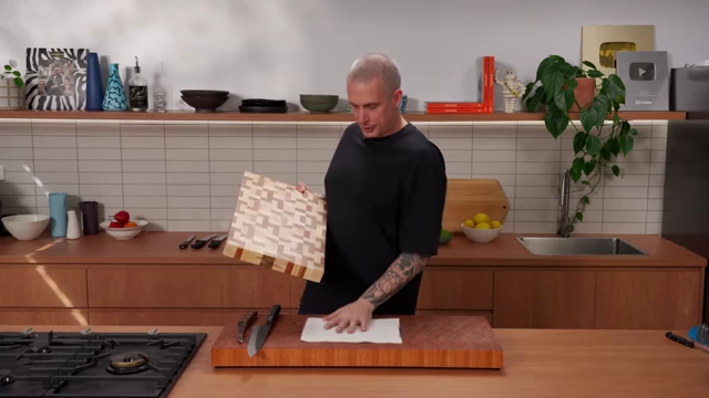 A chef demonstrates placing a non-slip mat under a cutting board for stability