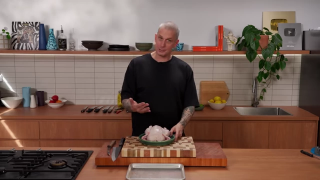 A whole raw chicken on a cutting board, ready for butchery