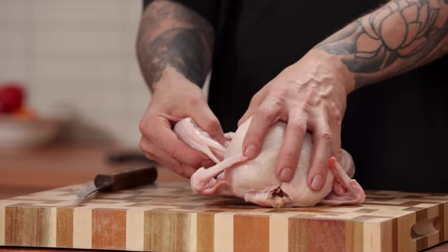 A chef separates the chicken leg from the body by bending it back to dislocate the joint