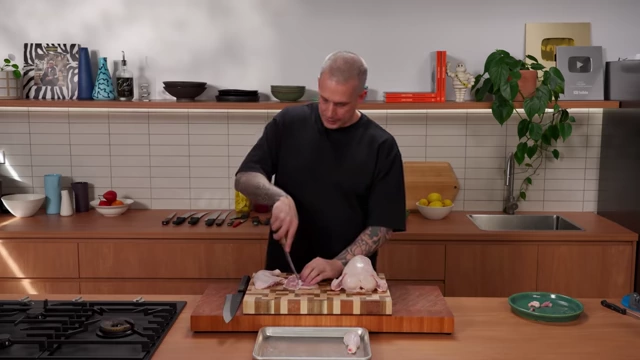 A chef bones a chicken thigh by carefully slicing along the bone with a boning knife