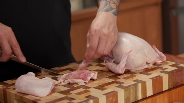 A boned chicken thigh lies on a cutting board, ready for cooking