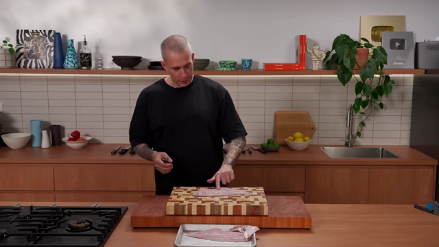 A chef points to the line of pin bones on a fish fillet