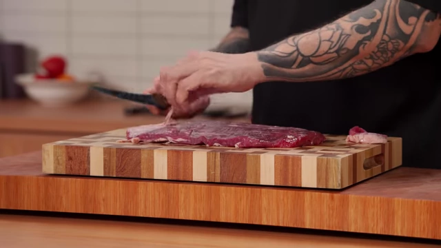 A chef removes silver skin from beef, showing the thin, separated layer of connective tissue
