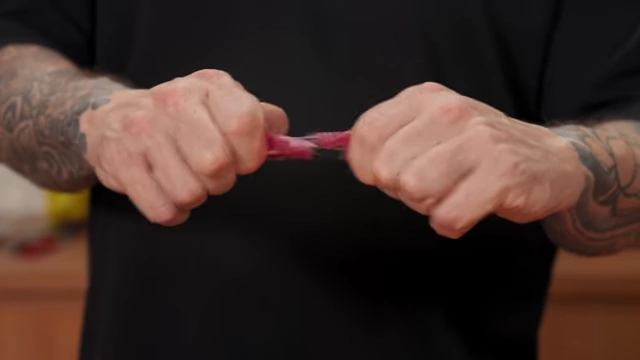 Hands easily pulling apart a piece of beef that was cut against the grain, showing its tenderness