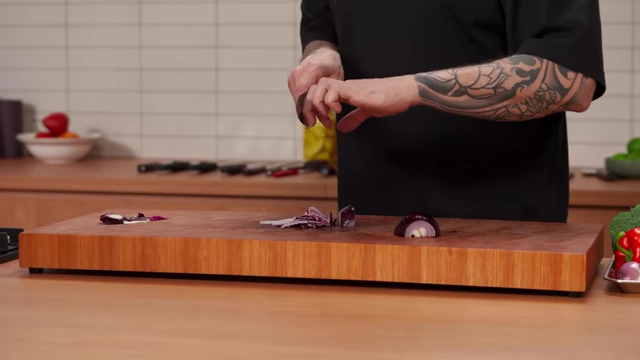 A chef shows how to adjust the "claw" grip by opening the hand slightly as the onion gets smaller