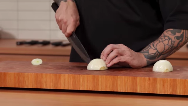 A chef makes vertical slices into the onion to prepare for a fine dice