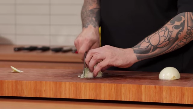 A chef finely dices an onion, creating very small, uniform pieces
