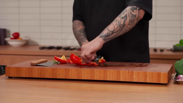 A chef removes the white membrane from the inside of a red bell pepper