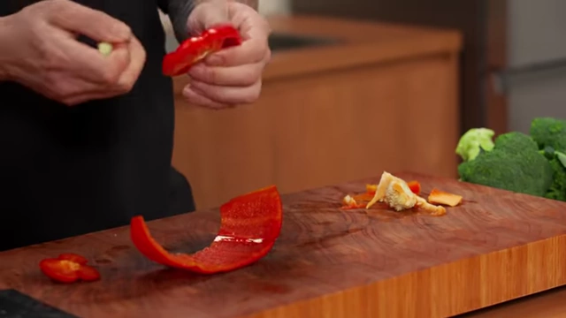 A chef displays the cleaned segments of a red bell pepper, ready for cutting