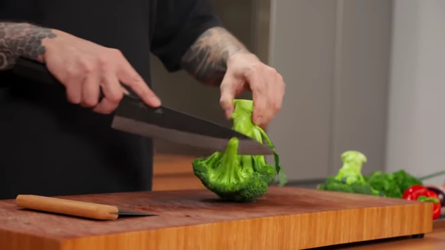 A chef cuts broccoli florets from the main stem