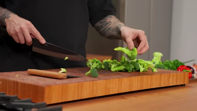 A chef splits a large broccoli floret stem to create smaller, more manageable pieces