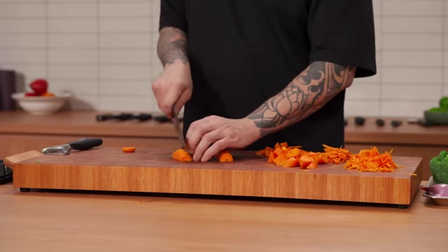 A chef quarters a carrot lengthwise for dicing