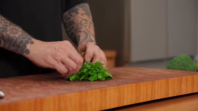 A close-up shows parsley leaves tightly rolled into a cigar shape, ready for a single, precise slice