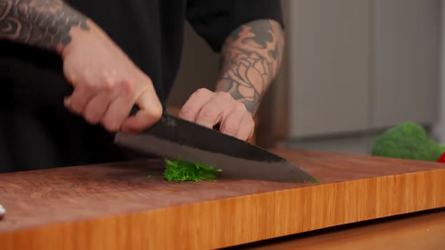 A chef finely chops rolled parsley leaves with a single pass of the knife