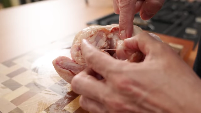 A chef feels for the wishbone inside the chicken's neck cavity