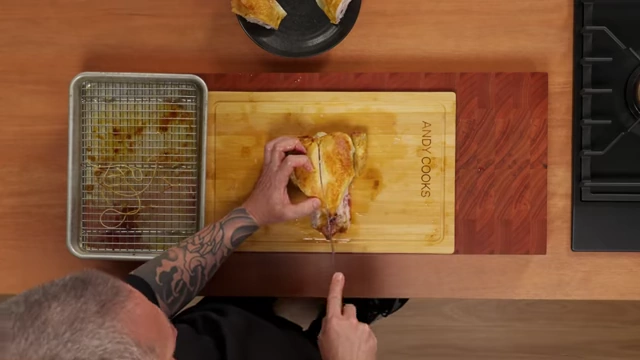 An overhead view of a chef carving a roasted chicken breast, following the sternum bone