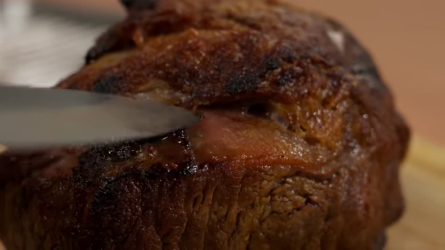 A close-up of a roasted beef joint, showing the subtle lines of muscle fibers that indicate the grain direction