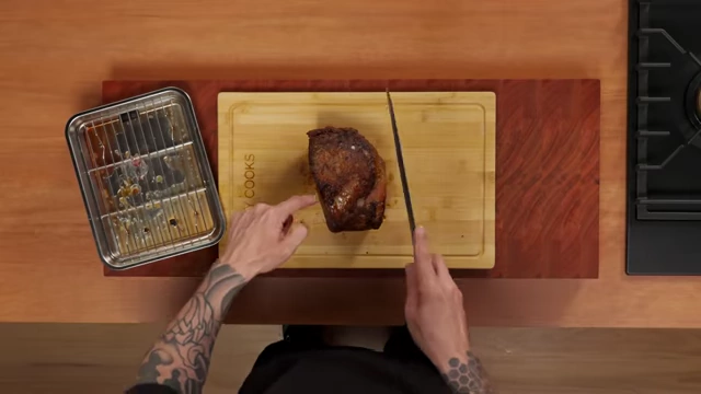 An overhead view of a roasted beef joint on a cutting board, with lines indicating the direction of the grain for proper carving