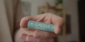 A hand holding a rechargeable AA battery, suggesting it as a practical solution for the TourBox Elite Plus