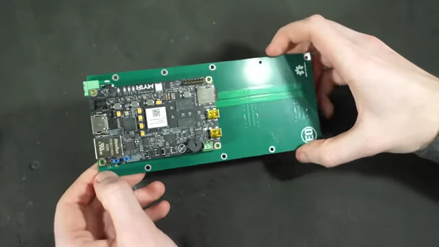 A person holding the custom backplane with the Zynq board attached