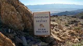 Ryan Holiday's book "Discipline is Destiny" stands on a rocky landscape.