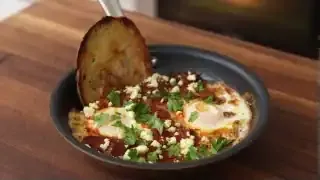 Shakshuka with feta and herbs in a pan with a side of toasted bread