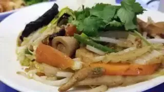 A colorful, fresh plate of ethnic food with various vegetables and garnishes.