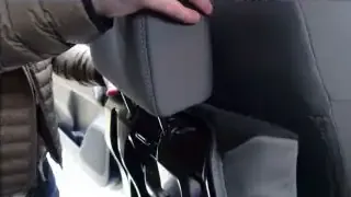 A user demonstrates how to store a removed headrest into designated holes on the back of the seat frame