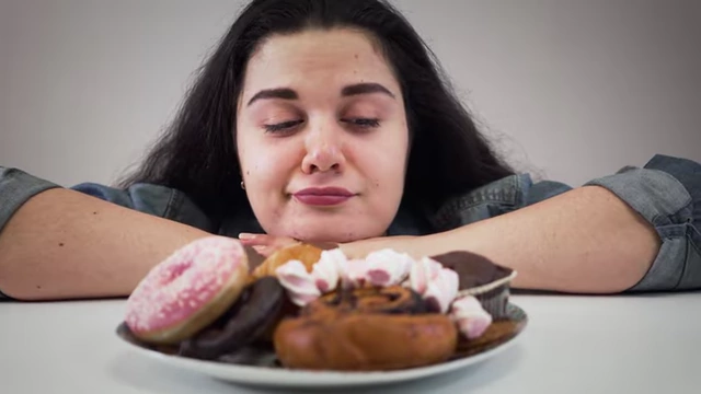 A person looking wistfully at a plate of donuts and pastries, indicating strong food chatter