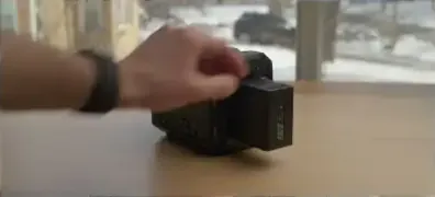 A hand sliding a BPU battery into the camera's battery slot