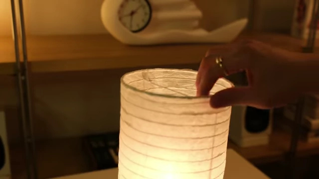 Hands carefully assembling the lamp, emphasizing the delicate paper and potential for glue coming off