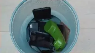 Multiple old phones and a landline receiver in a wastebasket, symbolizing the removal of distractions