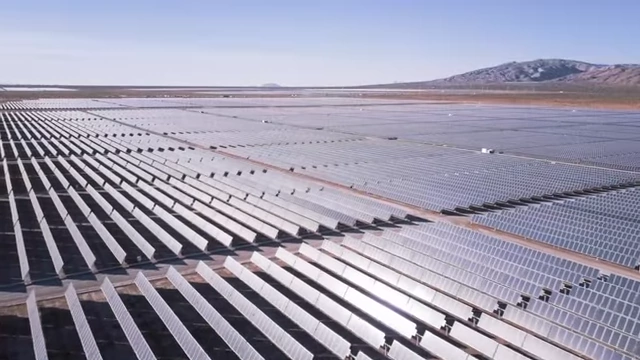An aerial view of a vast solar farm under a clear sky.