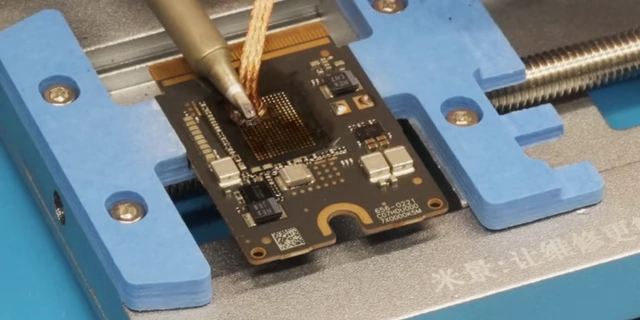 Linus using solder wick to clean residual solder from the Mac Mini SSD module