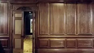 A grand room featuring extensive wooden paneling, including numerous raised and fielded panels on the walls and doors.