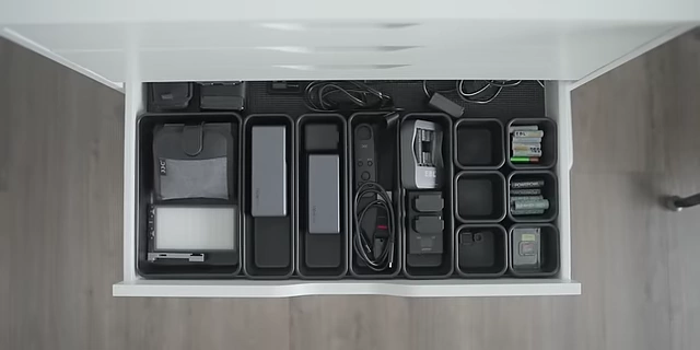 A drawer efficiently organized with interlocking modular containers, ideal for small electronic accessories and tools.