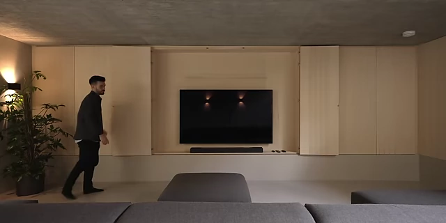A wall of concealed storage units in a living room, with a TV discreetly integrated.
