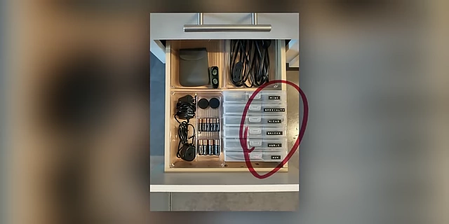 An organized drawer featuring small, labeled containers for cables, batteries, and other miscellaneous items.