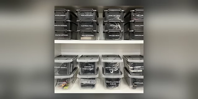 Shelves filled with clear, labeled storage containers for various electronic accessories and cables.